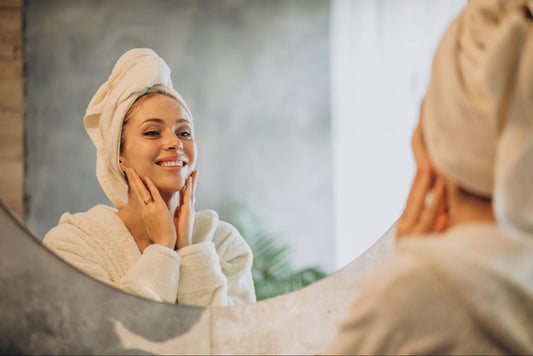 A woman in a bathrobe gazes at her reflection in the mirror, contemplating her appearance.