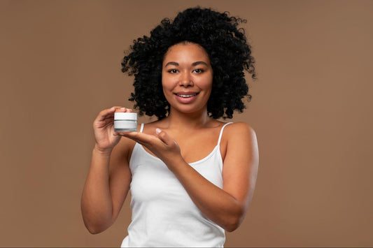 Beautiful African American woman smiling while holding a jar of skin cream in her hand.