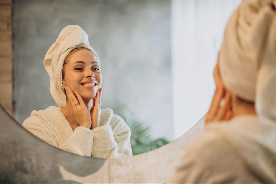 A woman in a bathrobe gazes at her reflection in the mirror, contemplating her appearance.