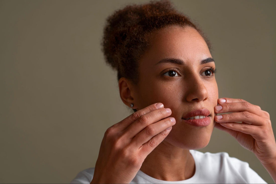 A woman gently touches her face with her hands, conveying a moment of contemplation or self-reflection.
