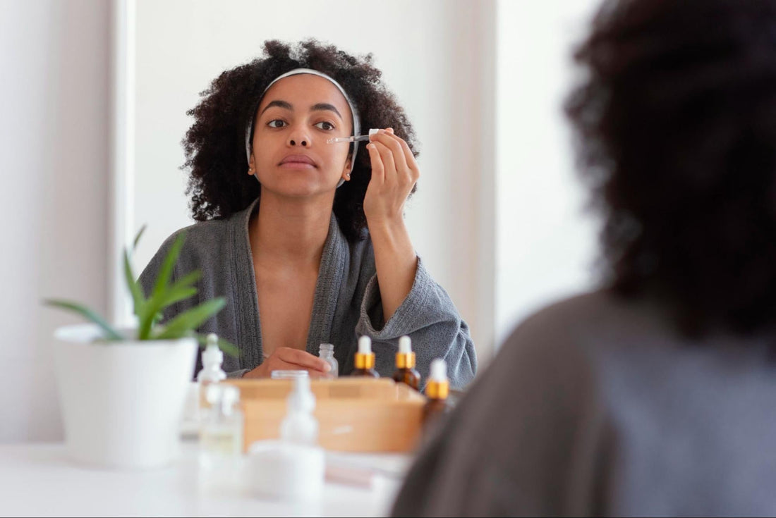 A woman applies makeup while gazing into a mirror, focusing on her reflection and enhancing her features.