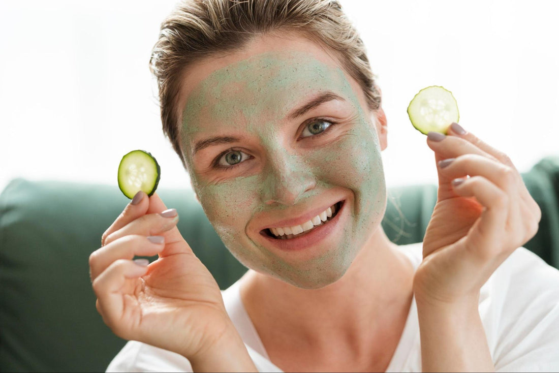 A woman wearing a green face mask with cucumber slices placed over her eyes, relaxing in a spa-like setting.